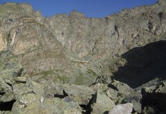 Ambiente montano roccioso con al centro in lontananza la caserma della traversette e sopra la catena montuosa che svetta.