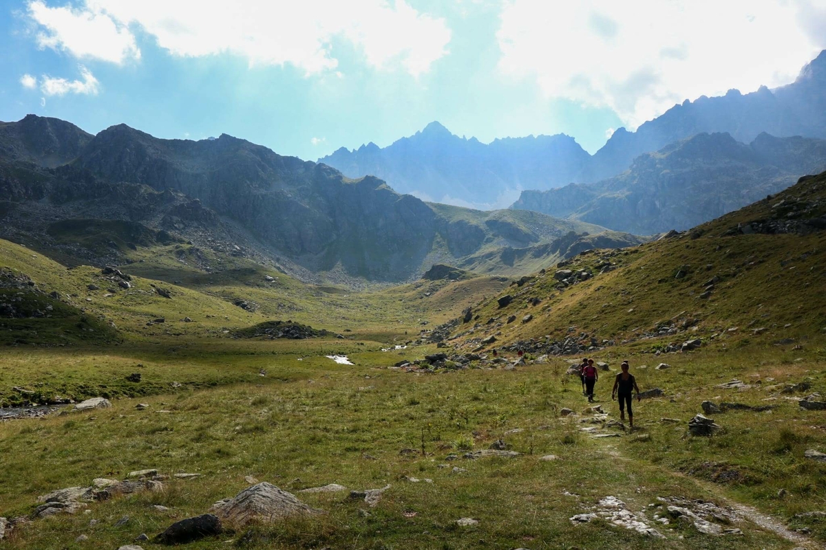 ampio pianoro erboso con alcuni escursionisti. montagne sullo sfondo