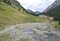 Sentiero montano che corre lungo il torrente Vallanta, sulla destra. Intorno praterie alpine e larici verdi